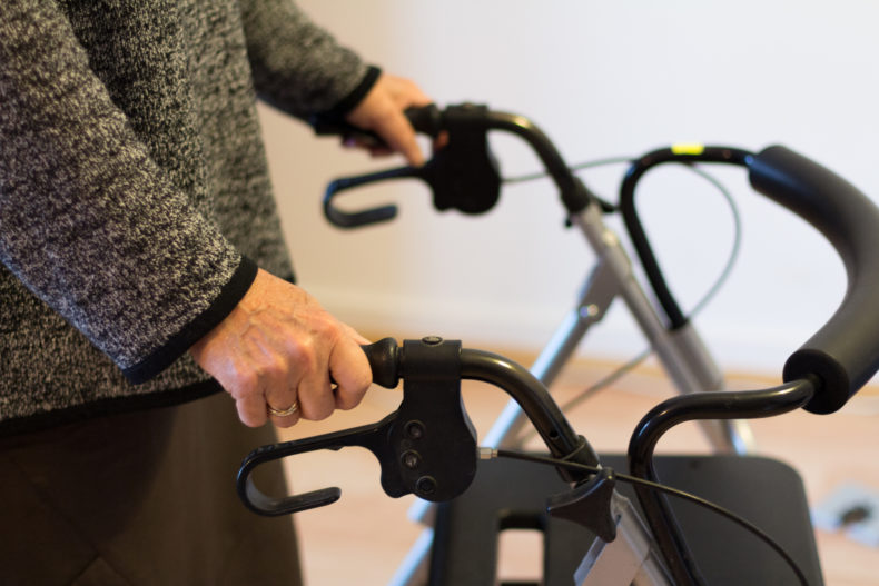 Eine betagte Frau stützt sich auf ihren Rollator.